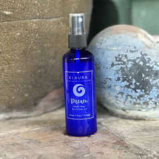 Blue spray bottle labeled 'Ktaura' on a wooden surface with a stone background